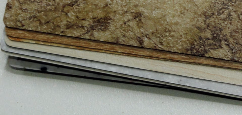 Mép của một xấp mẫu laminate xếp chồng. Dưới mặt vân đá nâu của mẫu trên cùng là một dải nâu đỏ gồm nhiều lớp mỏng, bên dưới là các mẫu khác có mép sáng màu hoặc xám.