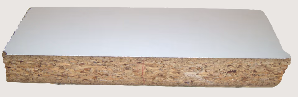 Một mẩu ván dăm phủ melamine trắng nhìn chéo từ mép cắt. Mặt trên là một lớp trắng rất mỏng nằm sát lên lớp dăm gỗ màu nâu vàng, không thấy lớp keo nào ở giữa. Hai đầu mẩu ván bị gãy, lớp trắng sứt nham nhở theo cốt.