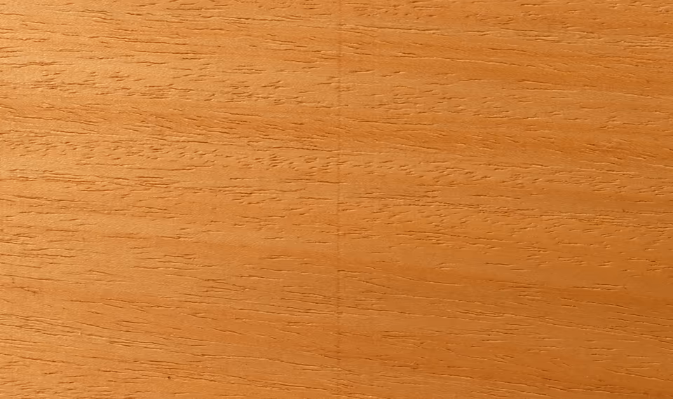 Mặt một tấm veneer lạng màu vàng cam nhạt, thớ gỗ chạy ngang, những vệt lỗ mạch nhỏ li ti, không có mắt gỗ hay vết nứt.